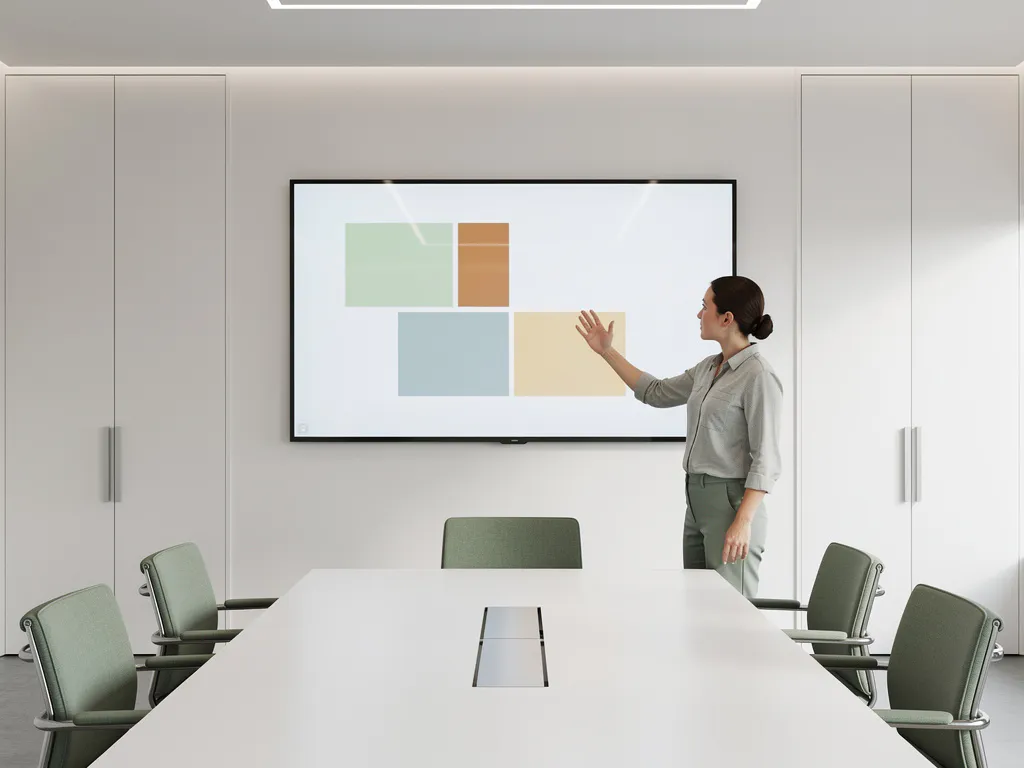 Persoon wijst naar content op groot 90-inch touchscreen in minimalistisch vergaderruimte met saliegroen en wit interieur.